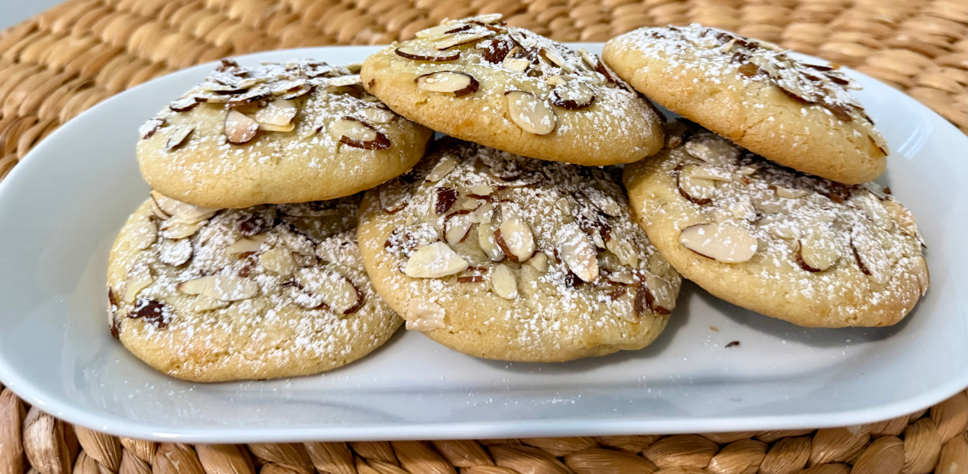 Almond cookies dusted with powdered sugar on a white platter